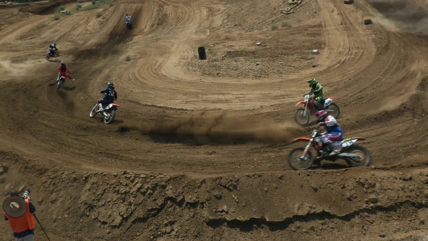 Dirt bikes riding on a track and kicking up dust