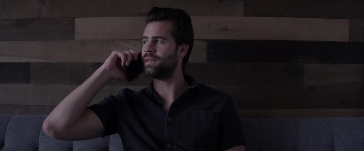 A man sitting on a couch answering his phone