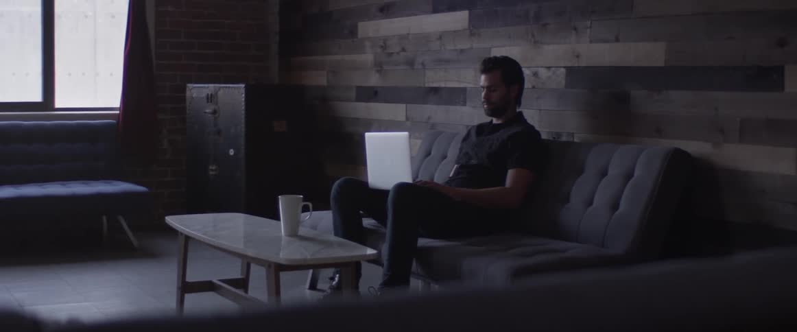 A man that is sitting on a couch with a laptop