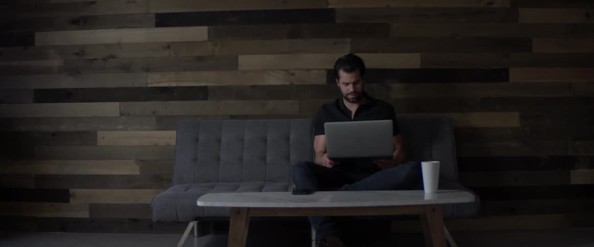 A man talking on his phone while reading his laptop