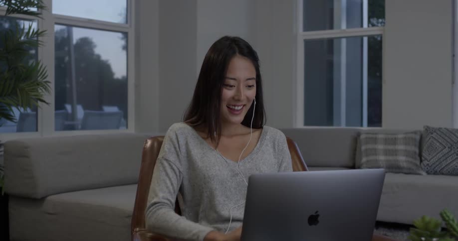 Woman sitting at a table video chatting with earbuds