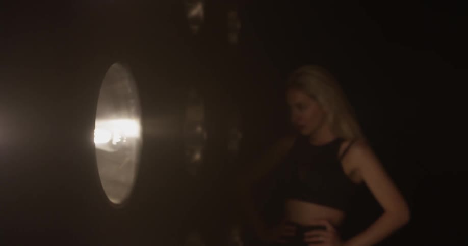 A lot of lights turning on to reveal a woman on stage
