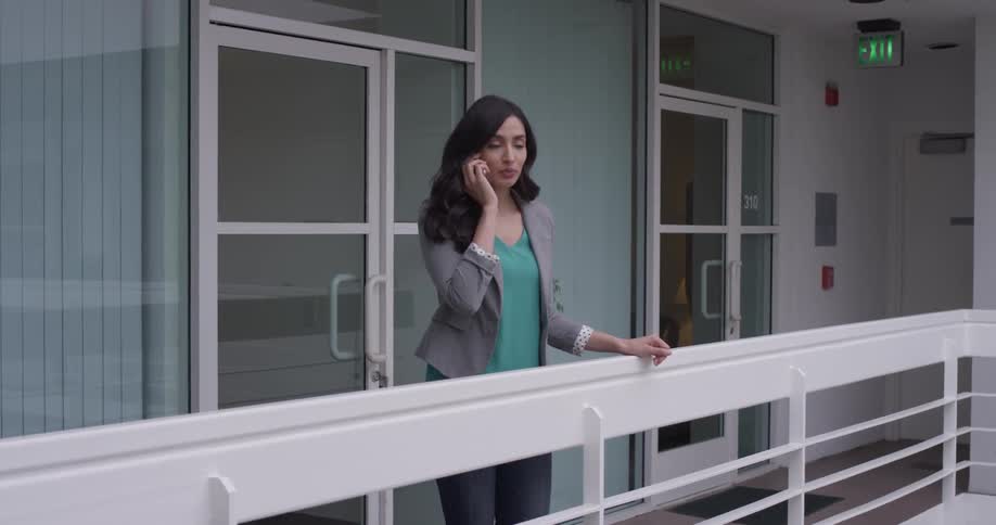 A woman talking on a cellphone standing on a balcony