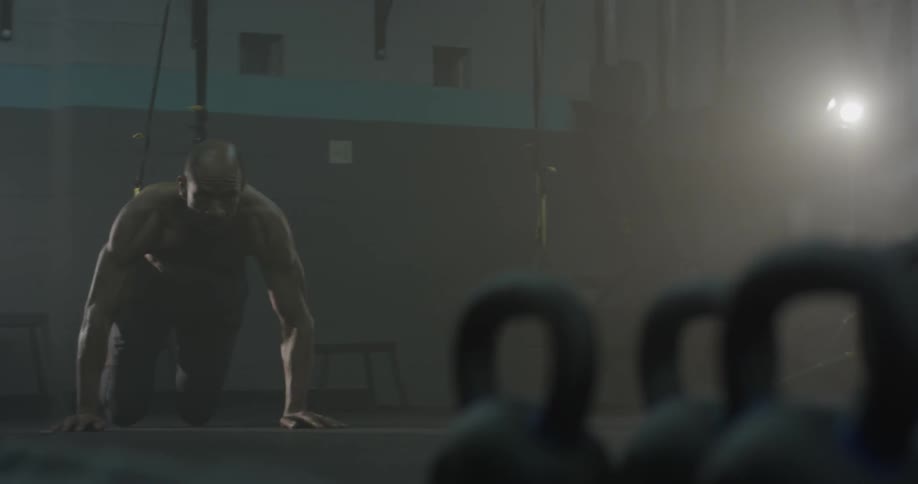 A man walking up to some straps in a gym