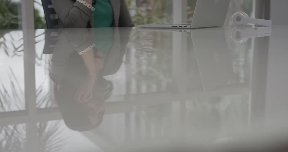 A woman typing on a laptop and picking up her phone