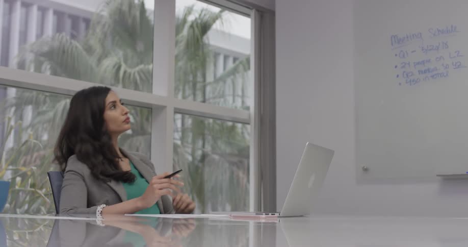 A woman tapping her pen while thinking in an office