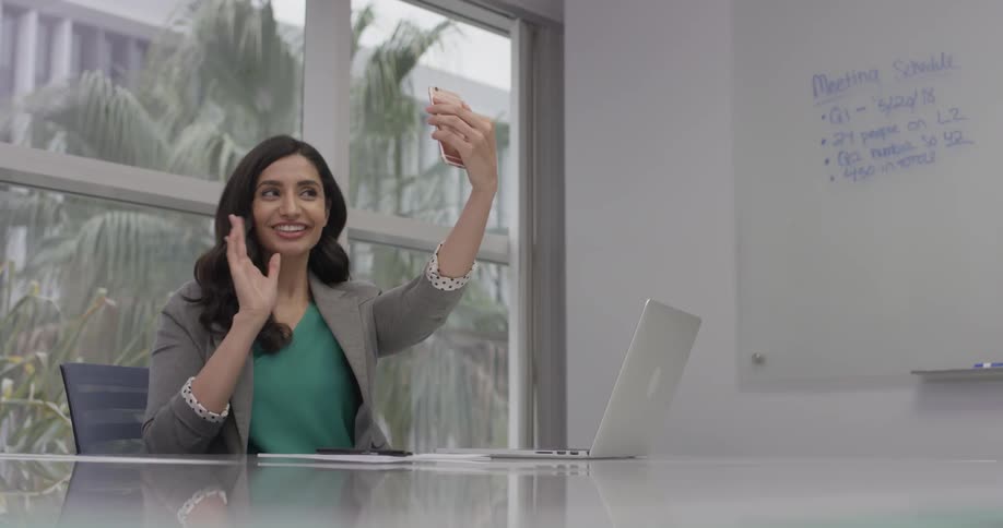A woman typing on a laptop and picking up her phone
