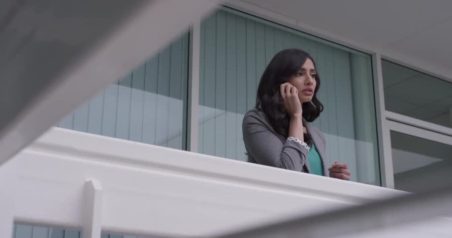 A woman standing on a balcony talking on a phone