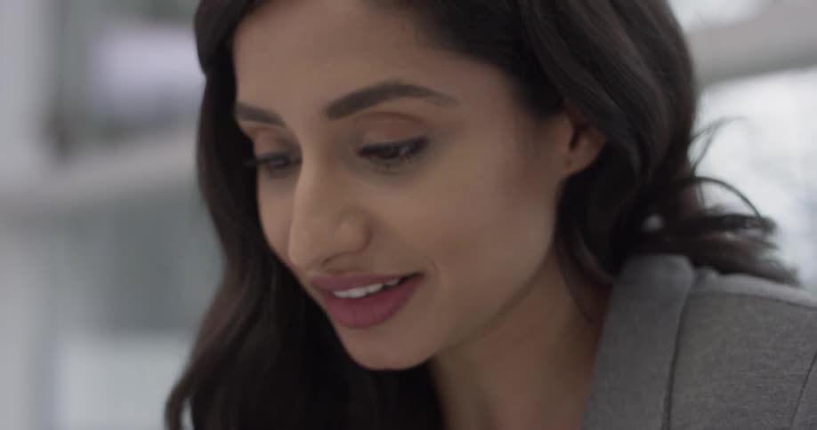 A woman is looking down while talking and fixes her hair