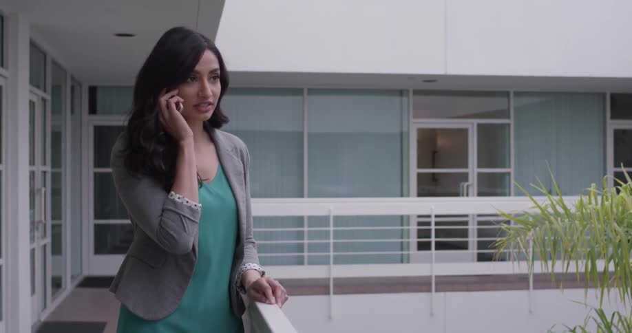 A woman leans against a railing talking on the phone