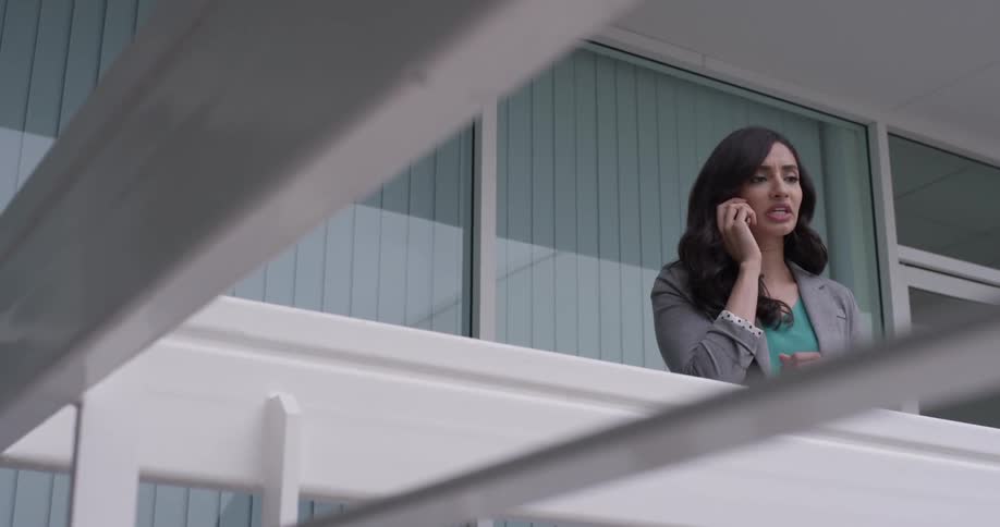 A woman walking on a balcony talking on a phone