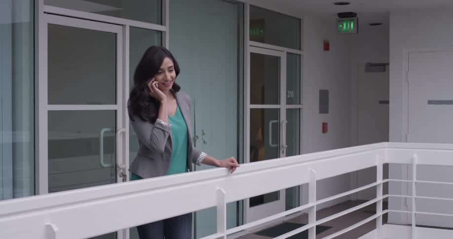 A woman talking on a cell phone on a balcony