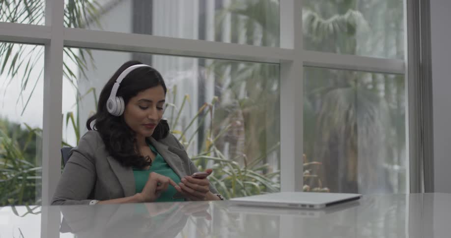 A woman wearing headphones and relaxing at work