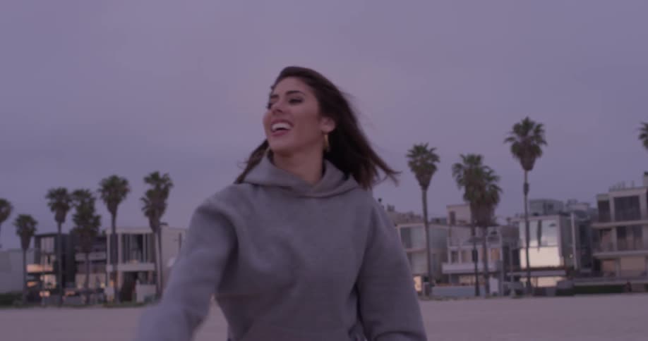 A woman on the beach catches then throws a football