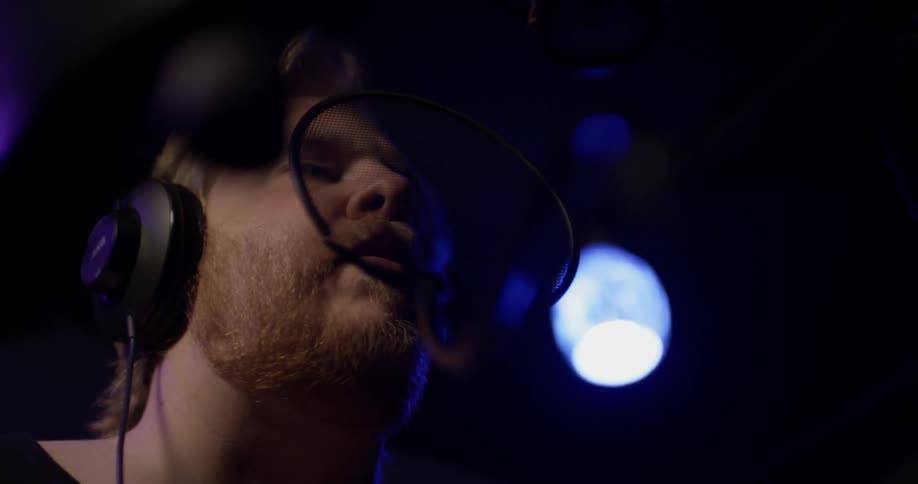 Man with headphones on sings into microphone