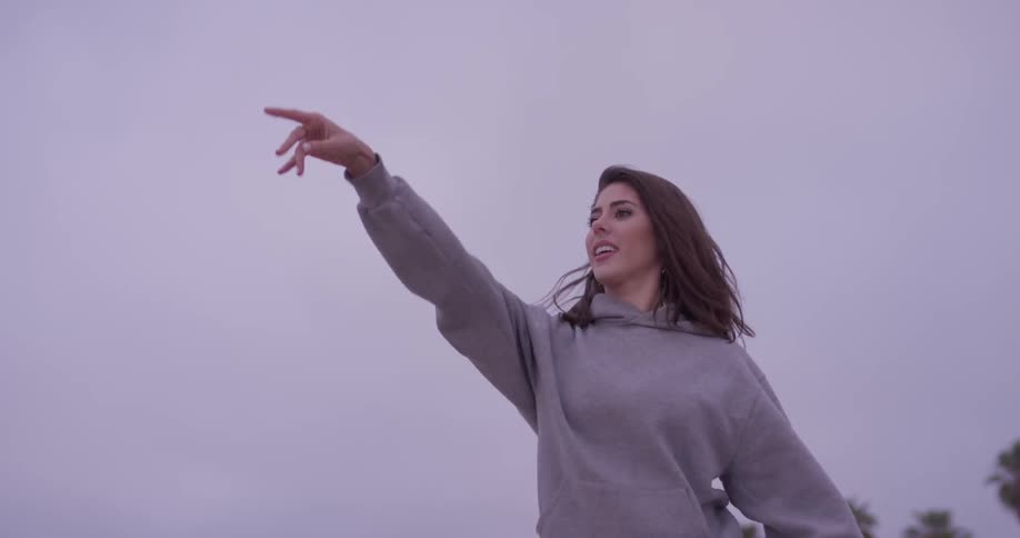 Woman throwing a football up in the air at dusk