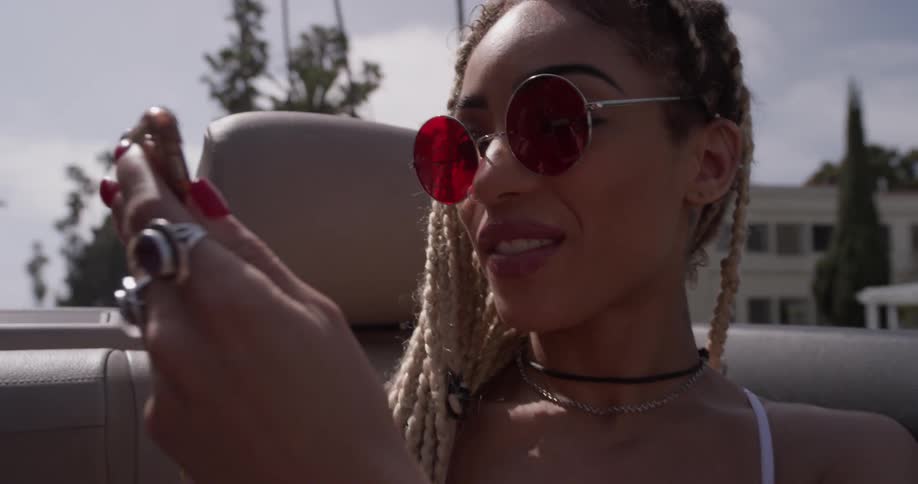 Woman rides in a convertible in the city taking pictures
