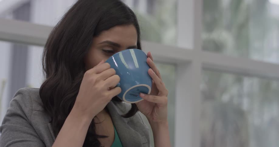 A woman sipping a cup of tea at work