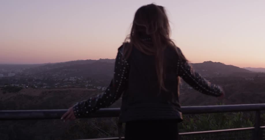 Backside of a woman wearing a leather jacket looking out over the hollywood hills