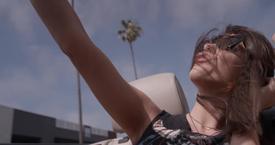 Woman rides in a convertible and takes a picture of herself
