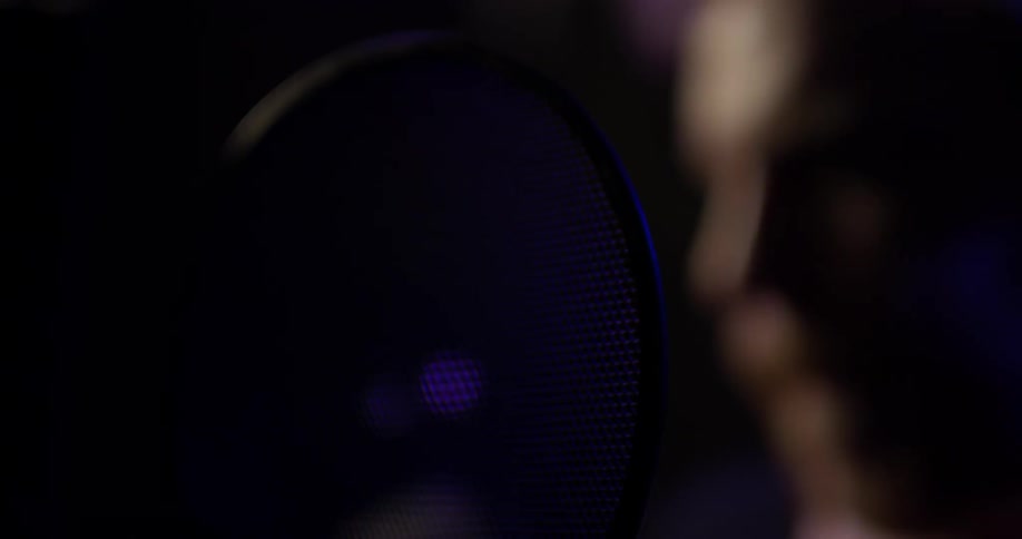 A man singing into a microphone in a studio