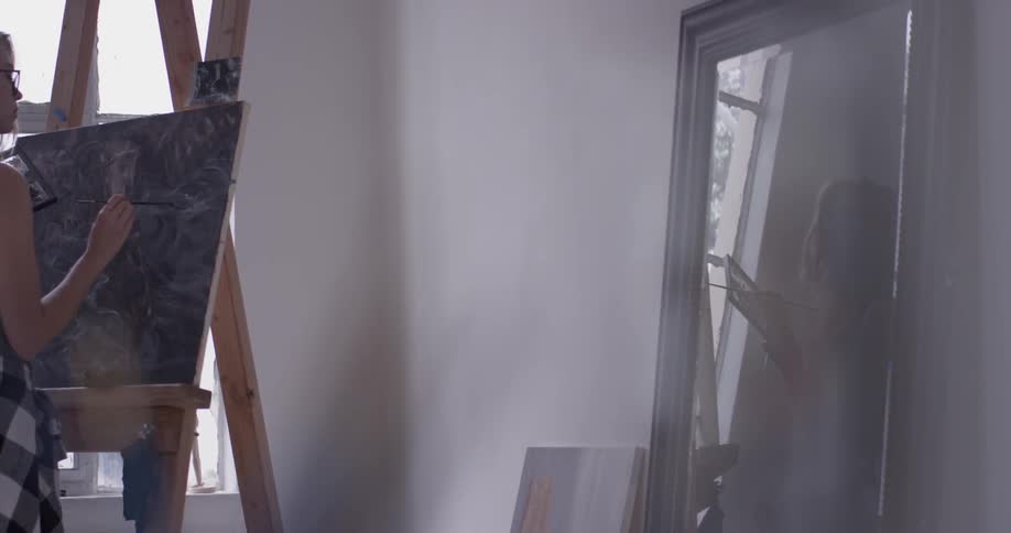 Woman painting on canvas with reflection also shown in mirror