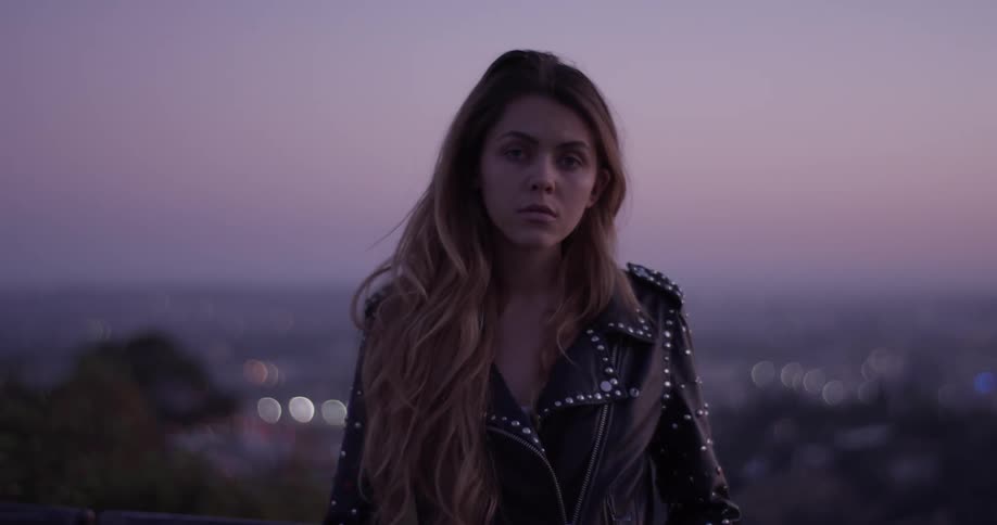 Woman stands outside at sunset looking worries