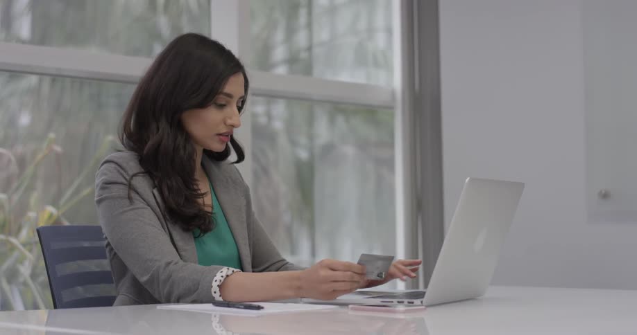 Woman typing a credit card number into a laptop