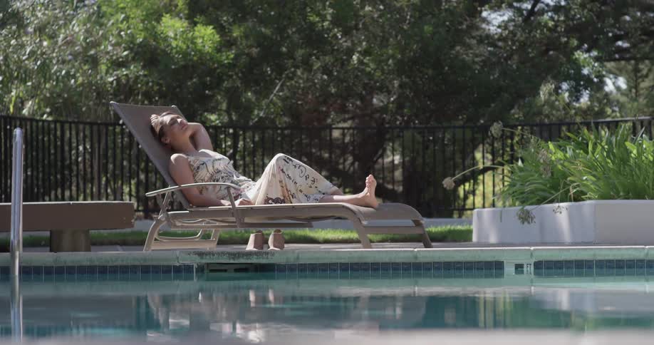 Woman lounges on a chair next to a pool