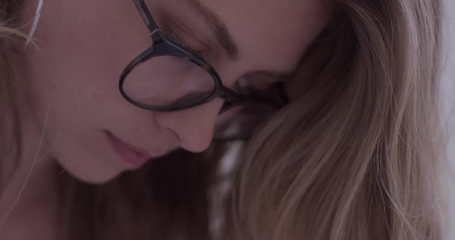 A woman in glasses looking at a piece of paper