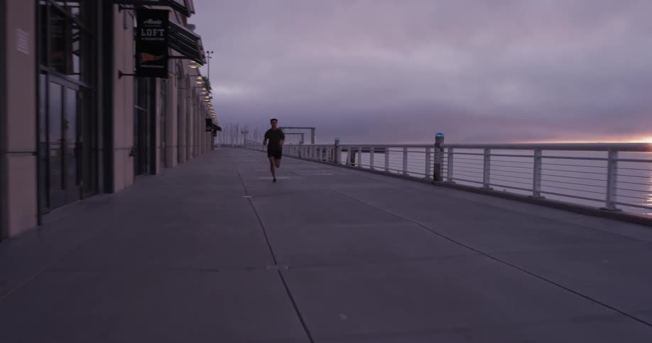 A man running down a pier next to some water