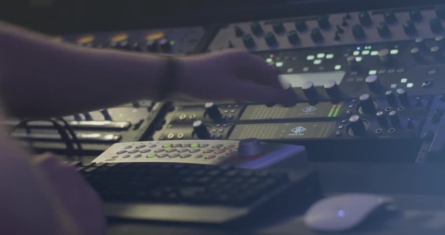 Arms and hands of a man working a sound system board