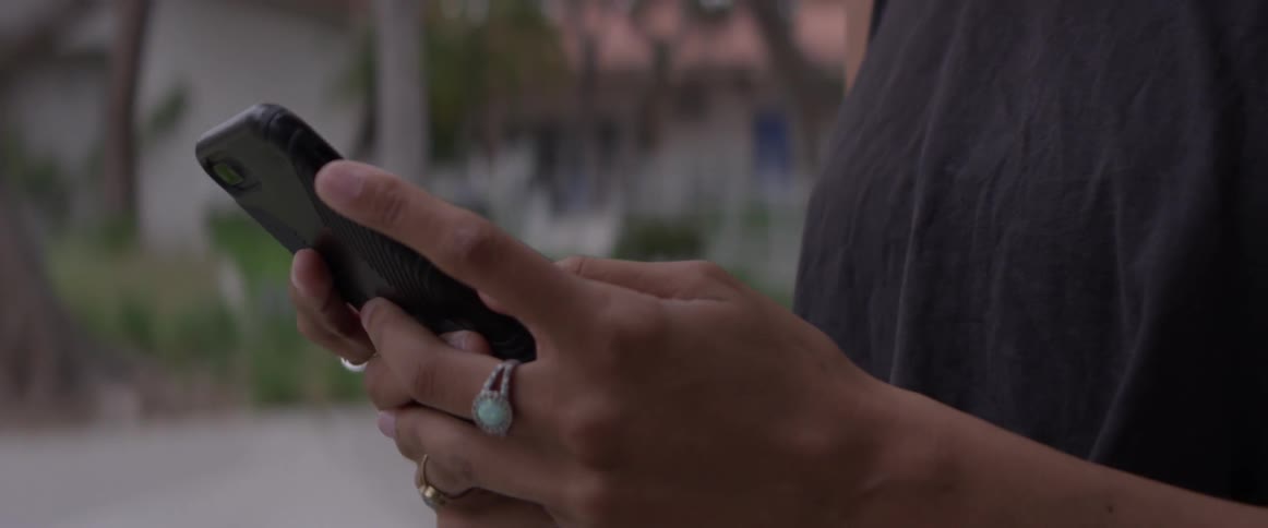 A person is using his phone out in the yard