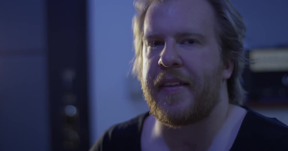 A man in a recording studio tilting up and looking at someone
