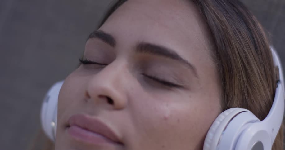 A woman puts on headphones and leans her head back to relax to the music