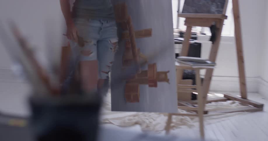 A woman picking up a painting in a studio