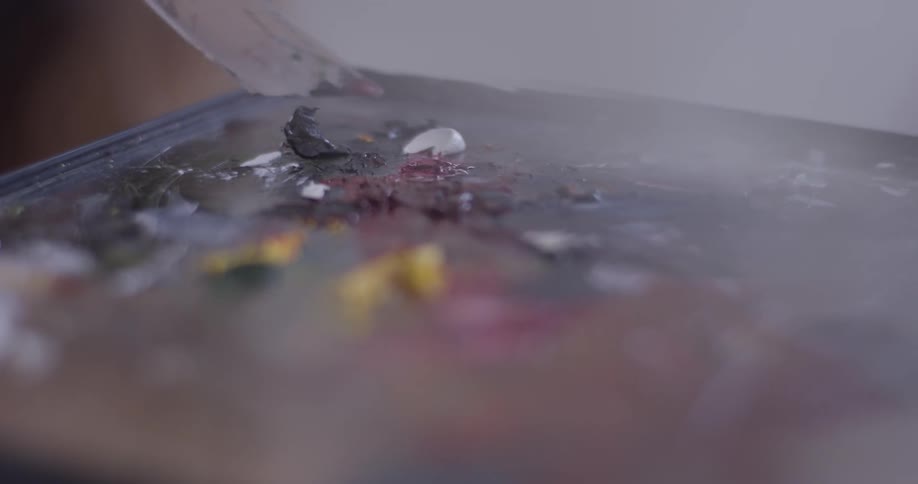 A person painting with a knife on a canvas