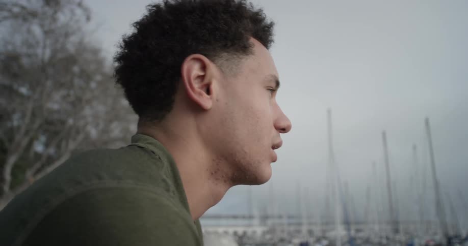 A man standing at the edge of a marina taking out headphones