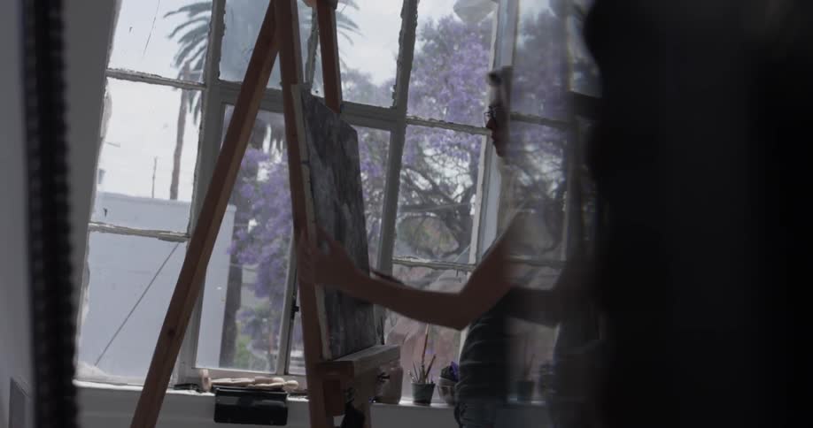A woman putting a painting on a easel
