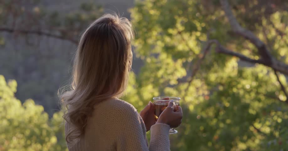 A woman is outside drinking from a glass
