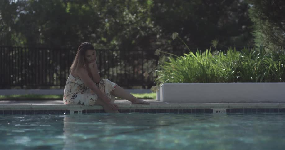 A woman is sitting by the pool