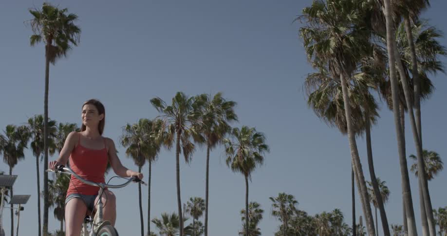 Woman rides a bike near palm trees