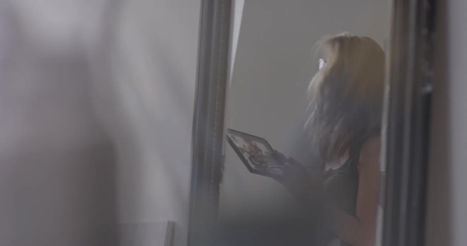 Woman shown in reflection holding easel and painting