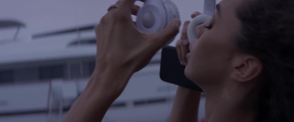 Woman putting on headphones on the sidewalk
