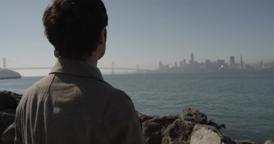 A man looking at a city across some water