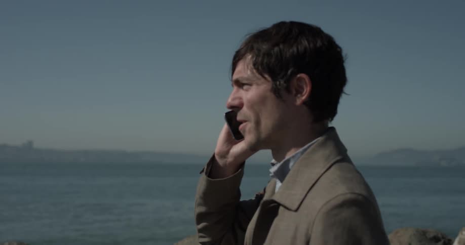 A man is talking on a phone by the beach