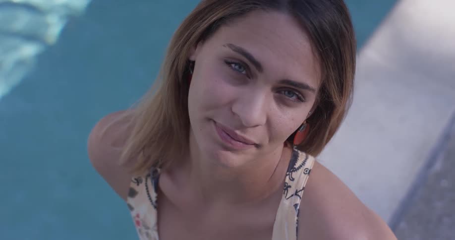 A woman sitting next to a pool on a sunny day