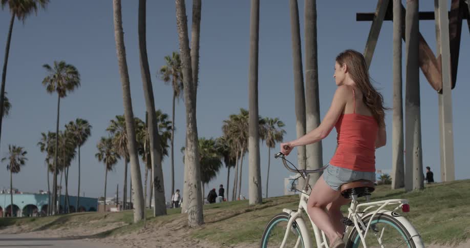 Woman riding a bicycle down a siewalk