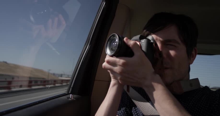 Man taking a photo out of a car window