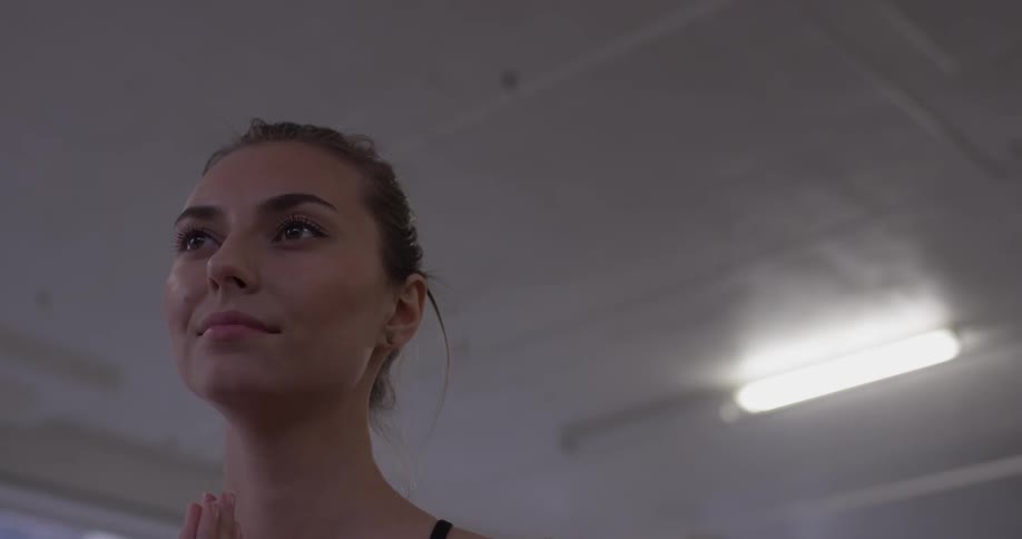 Woman stands in a room smiling and looks down